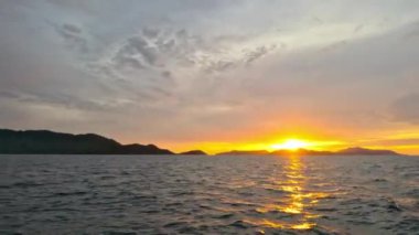 Denizin üzerindeki gün batımının görüntüsü bir tekneden denize açılırken. Deniz üzerinde akşam güneşinin sinematik manzarası.