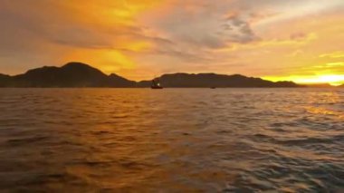 Denizin üzerindeki gün batımının görüntüsü bir tekneden denize açılırken. Deniz üzerinde akşam güneşinin sinematik manzarası.