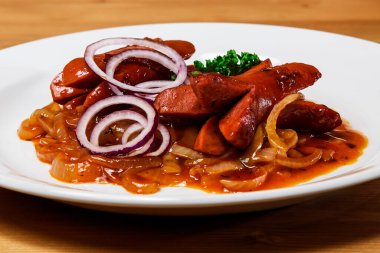 Kırmızı soğanlı kızarmış domuz ve beyaz tabakta maydanoz.