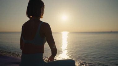 Kadın, plajda yoga pozunda meditasyon yapıyor. Yoga konsepti. El kadını sahilde nilüfer poz pratiği yapıyor.