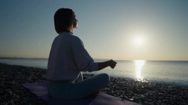 Gün batımında doğada yoga yapan genç bir kadının silueti. Aktif meditasyon rahatlatıcı bir kavram. Parkta kadın meditasyonu. Sunset spor eğlencesi konsepti. Yüksek kalite 4k görüntü