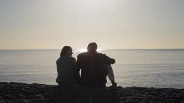 Çocuklu genç bir aile güzel bir gün batımına bakıyor. Baba, anne ve çocuk deniz kenarında oynuyorlar. Etkin sağlıklı yaşam tarzı konsepti.