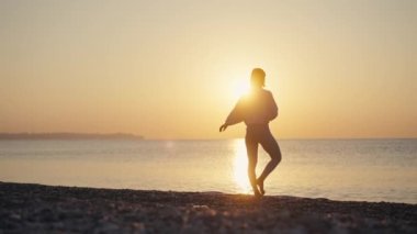 Siluet Kadın, yaz tatili plaj mutluluğu ve rahatlama ile meditasyona yoga pozu veriyor. Yogayla sakin kadın egzersizleri okyanus sahilinde altın günbatımında meditasyon yapar. Ruh Sağlığı