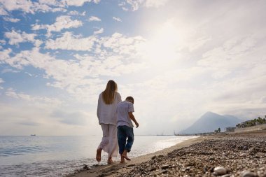 Anne ve oğlu gün batımında sahilde yürüyor. Yüksek kalite fotoğraf