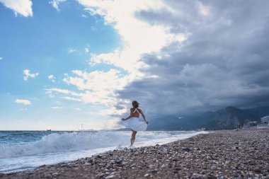 Sahilde koşan mutlu genç bir kızın arka görüntüsü. Yüksek kalite fotoğraf