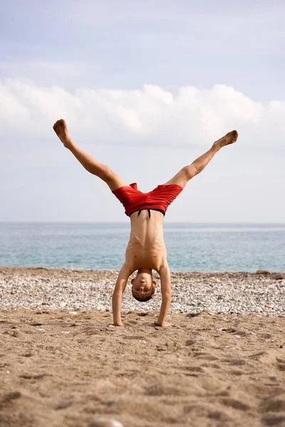 stock image kid does acrobatics on the beach. High quality photo