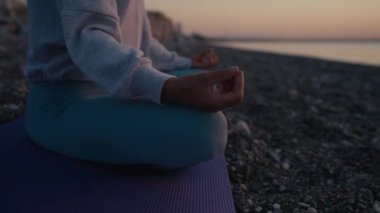 Kadın, plajda yoga pozunda meditasyon yapıyor. Yoga konsepti. El kadını sahilde nilüfer poz pratiği yapıyor.