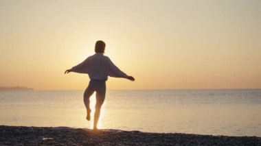 Siluet Kadın, yaz tatili plaj mutluluğu ve rahatlama ile meditasyona yoga pozu veriyor. Yogayla sakin kadın egzersizleri okyanus sahilinde altın günbatımında meditasyon yapar. Ruh Sağlığı