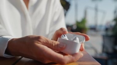 Genç kadın kablosuz kulaklık takıyor. Giyim kuşam. Ellerinde uçak kapsülleri, Apple takılabilir kulaklıklar.