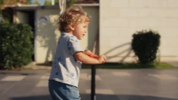 Kleine Jongen Kick Scooter Het Park Kleuterscholier Leert Rolschaatsen Glimlachend — Stockvideo