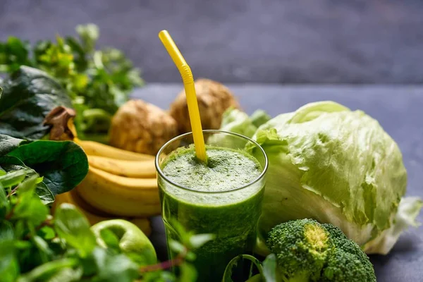 Jars of healthy green smoothie with fresh spinach on grey wooden table, closeup. Detox diet concept: green vegetables on wooden table