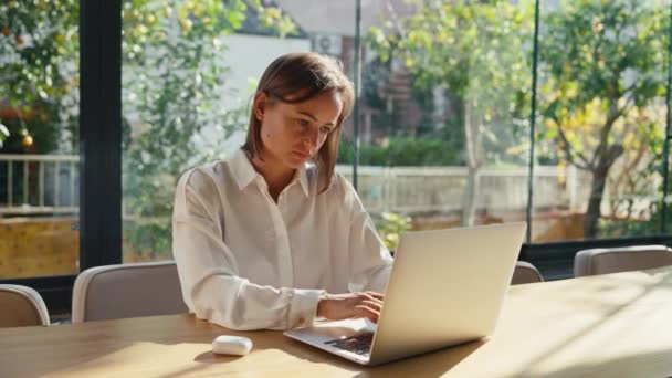机の上で長時間座り込み状態でコンピュータに取り組む疲れた女は激しい腰痛を感じている 若い女性がオフィスで首の痛みを持っているノートパソコンで作業しながら — ストック動画