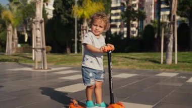 Parkta scooter süren küçük bir çocuk..