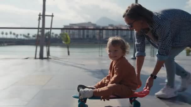 Mother Pushing Little Son Sitting Skateboard — Video Stock
