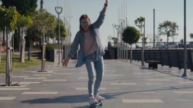 Young stylish teenage girl learning to ride skateboard. Trendy girl first time tries to ride skateboard. High quality 4k footage