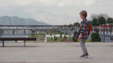 Schoolboy with his little brother riding on skateboard and having fun