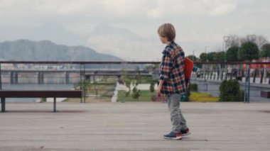 Schoolboy with his little brother riding on skateboard and having fun