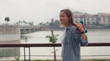 Wide portrait of a happy smiling skater girl sitting in a skatepark taking a moment to rest and enjoy herself on a sunny weekend. High quality 4k footage