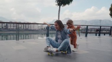 Cheerful son pushing his mother on a skateboard and laughing. Wild and crazy