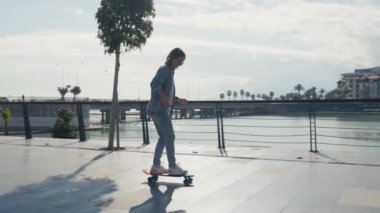 Young stylish teenage girl learning to ride skateboard. Trendy girl first time tries to ride skateboard. High quality 4k footage