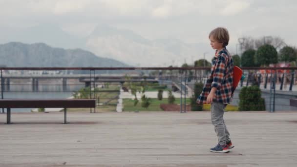 スケートボードに乗って楽しいです彼の弟と学校の少年 — ストック動画