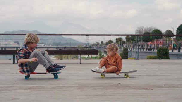スケートボードに乗って楽しいです彼の弟と学校の少年 — ストック動画