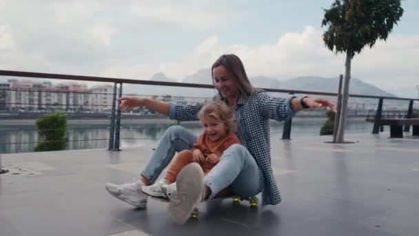 Mother Pushing Little Son Sitting Skateboard High Quality Footage — Vídeos de Stock