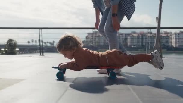 Mother Pushing Little Son Sitting Skateboard — Αρχείο Βίντεο