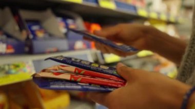 Young woman chooses protein bars in a store and reads the composition. Sport nutrition.