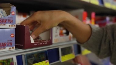 Young woman chooses protein bars in a store and reads the composition. Sport nutrition.