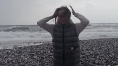 Young woman wearing a warm clothes on the beach in Turkey during a storm