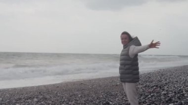 Young woman wearing a warm clothes on the beach in Turkey during a storm
