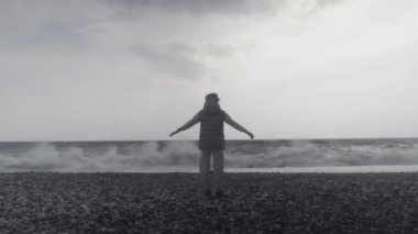 Young woman wearing a warm clothes on the beach in Turkey during a storm