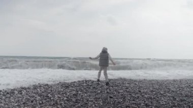 Young woman wearing a warm clothes on the beach in Turkey during a storm