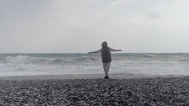 Young woman wearing a warm clothes on the beach in Turkey during a storm