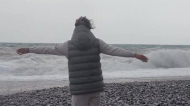 Young woman wearing a warm clothes on the beach in Turkey during a storm