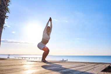 Güneş doğarken pratik Yoga sahilde genç sağlıklı kadın