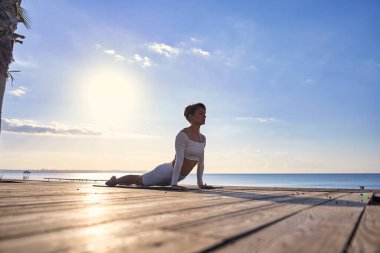 Güneş doğarken pratik Yoga sahilde genç sağlıklı kadın