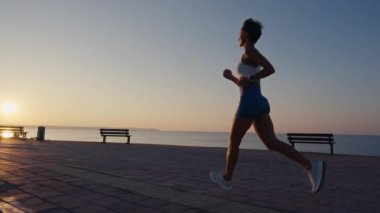 Koşan, beyaz kadın ve güneş doğarken formda olan, egzersiz amaçları, enerji ve güç için mavi gökyüzü. Mutlu sporcu, kardiyo ve dışarıda motivasyon, gülümseme ve sağlıkla egzersiz.