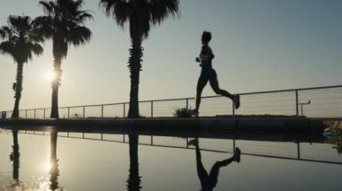 Koşan, beyaz kadın ve güneş doğarken formda olan, egzersiz amaçları, enerji ve güç için mavi gökyüzü. Mutlu sporcu, kardiyo ve dışarıda motivasyon, gülümseme ve sağlıkla egzersiz.