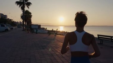 Gün batımında yolda koşan genç bir fitness sporcusu. Sporcu ayakları yolda koşuyor, ağır çekimde. Yüksek kalite 4k görüntü