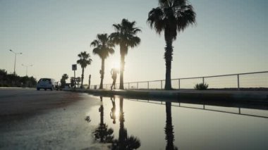 Koşan kadın sporcu gün batımı plajında koşuyor. Güzel bir gün batımında deniz kenarında antrenman yapan spor koşucusu bir kız ya da yazın tüm vücut uzunluğuyla gün doğumunda. Yavaş bir hareket yap. Yüksek kalite 4k görüntü