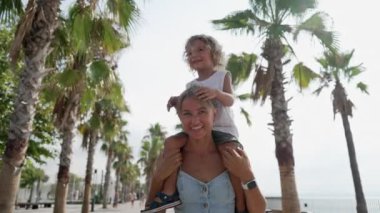 Küçük oğlu modern yel değirmenleriyle tarlada oturan genç anneye bakın. Mutlu bir aile. Çocuğun kollarını yana doğru uzattığı ve doğada birlikte yürüdükleri bir aile.