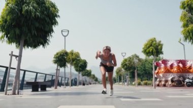 Genç beyaz kadın parkta koşuyor yoğun kardiyo egzersizi yapıyor. Yüksek kalite 4k görüntü