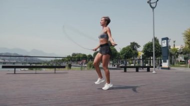 Atlama egzersizi yapan sportif bir kadın dışarıda ip atlıyor. Genç bir kadın spor sahasında ip atlıyor. Ağır çekim. Spor konsepti. 4K 'da kapatıyoruz, UHD. Yüksek kalite 4k görüntü