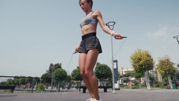 屋外でロープをスキップしてジャンプエクササイズをしているスポーティな女性 スポーツグラウンドでロープをスキップする若い女性 スローモーション スポーツコンセプト 4Kで閉じる Uhd 高品質の4K映像 — ストック動画