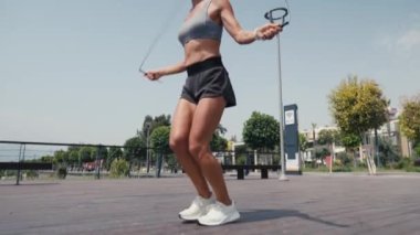 Atlama egzersizi yapan sportif bir kadın dışarıda ip atlıyor. Genç bir kadın spor sahasında ip atlıyor. Ağır çekim. Spor konsepti. 4K 'da kapatıyoruz, UHD. Yüksek kalite 4k görüntü