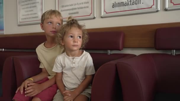 病院の廊下で待っている2人の少年 医学検査をしている子供たち — ストック動画