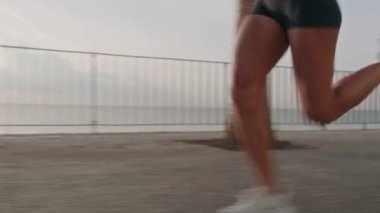 Genç fitness sporcusunun gün batımında gezinti güvertesinde koşarkenki görüntüsü. Yüksek kalite 4k görüntü