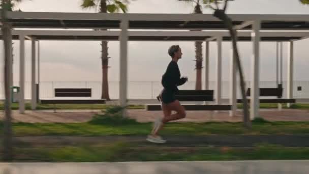 Genç Fitness Sporcusunun Gün Batımında Gezinti Güvertesinde Koşarkenki Görüntüsü Yüksek — Stok video